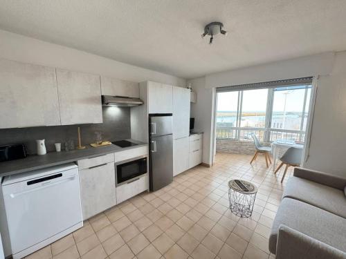 une cuisine avec des armoires blanches, une table et un canapé dans l'établissement 19 Cocon Familial Vue Mer, à Valras-Plage