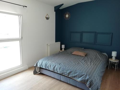 une chambre avec un lit et un mur bleu dans l'établissement Longère Golfe du Morbihan avec piscine extérieure, à Plescop