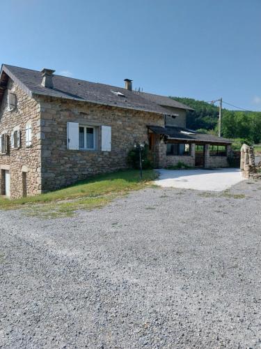 une maison en pierre avec une allée en gravier en face de celle-ci dans l'établissement La Bergerie Maison familiale, à La Salvetat-sur-Agout