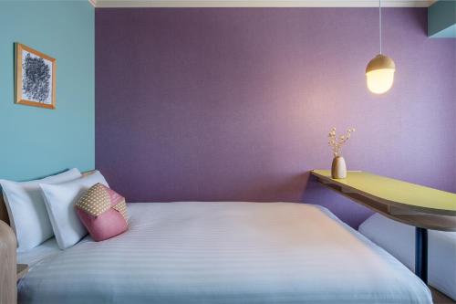 a bedroom with a bed and a purple wall at OMO7 Asahikawa by Hoshino Resorts in Asahikawa