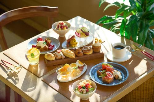 a table topped with plates of food and cups of coffee at OMO7 Asahikawa by Hoshino Resorts in Asahikawa