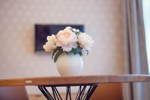 a white vase with pink flowers sitting on a table at LeonArt Living 21 in Graz