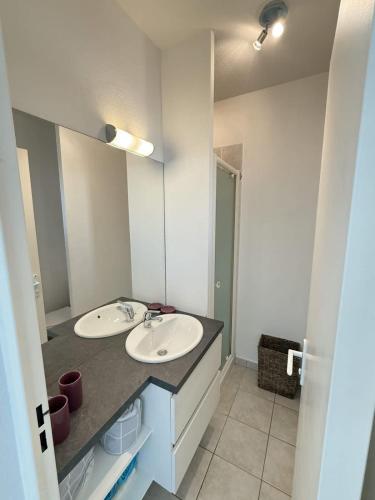 une salle de bain avec deux lavabos et un grand miroir dans l'établissement Evasion Valras Appartement Cosy avec Piscine, à Valras-Plage