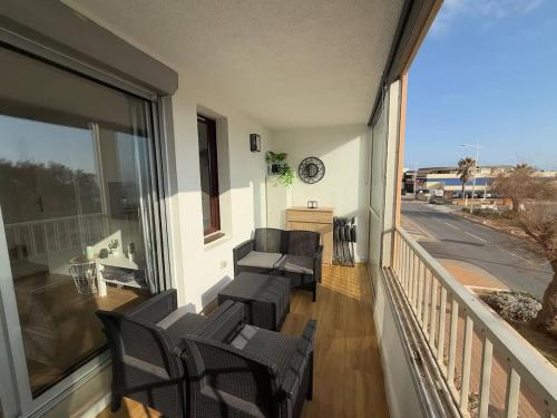 un balcon avec des chaises et un canapé sur un porche dans l'établissement Valras-Loc Casino Beach - Moderne et Vue Mer, à Valras-Plage