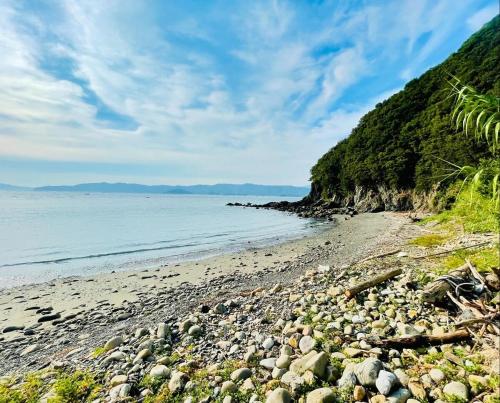 a beach with rocks and the ocean on a cloudy day at ビーチ付きのプライベートスペースで海水浴して焚き火やバーベキューが楽しめる1日1組貸切宿 in Otsuki