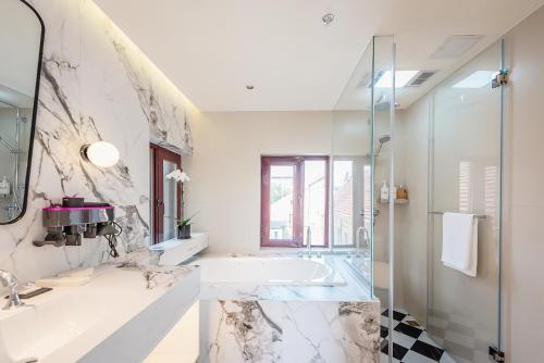 a bathroom with a tub and a sink and a shower at TUIWA Garden Holiday Villa in Qingdao