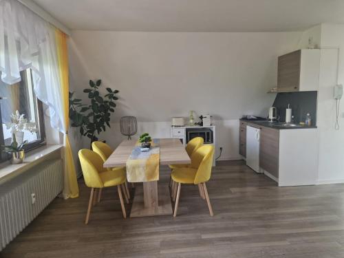 a kitchen with a dining table and yellow chairs at Ferienwohnung in Schonwald im Schwarzwald