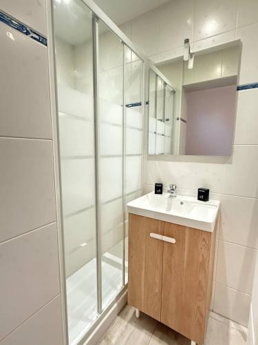 une salle de bain blanche avec un lavabo et une douche dans l'établissement Appartement en Rez-de-Chaussee a Deux Pas de la Plage, à Valras-Plage
