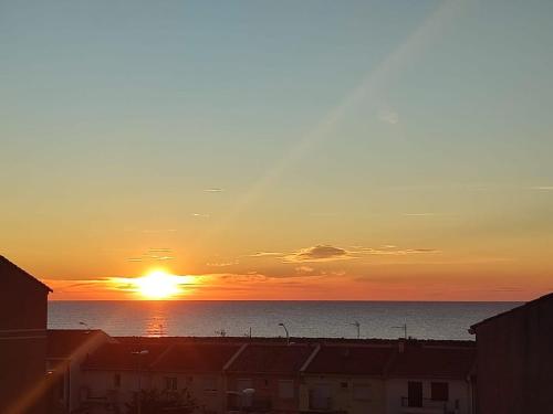 un coucher de soleil sur l'océan avec le soleil dans le ciel dans l'établissement Duplex avec Vue Mer A Deux Pas de la Plage, à Valras-Plage