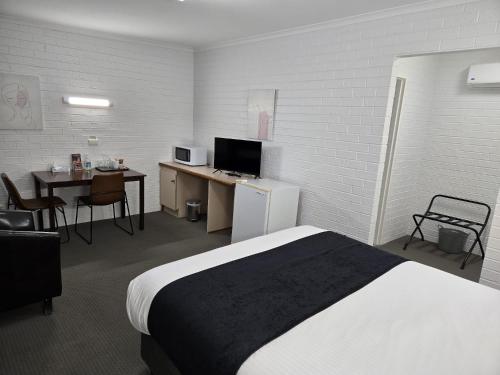 a hotel room with a bed and a desk and a table at KooWeeRup Motel in Koo-Wee-Rup