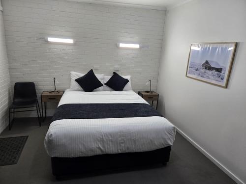 a bedroom with a bed and two tables and a chair at KooWeeRup Motel in Koo-Wee-Rup