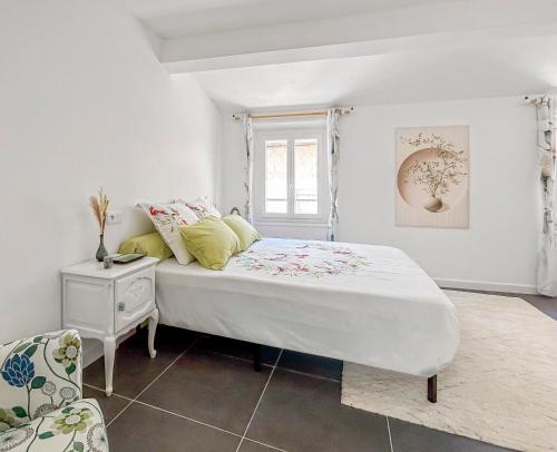 une chambre blanche avec un lit et une chaise dans l'établissement Appartement cosy et lumineux au cœur de Cogolin, à Cogolin