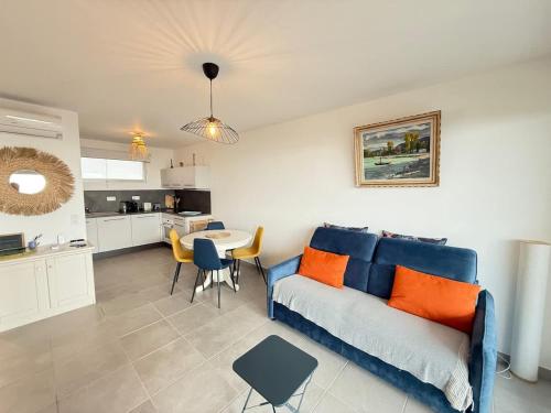 un salon avec un canapé bleu et une cuisine dans l'établissement Valras-Loc Archipel Capri - Murmures des Vagues, à Valras-Plage