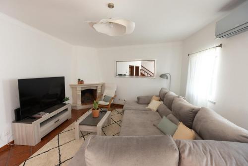 a living room with a couch and a tv at Casa Marilyn in Vila Nova de Milfontes