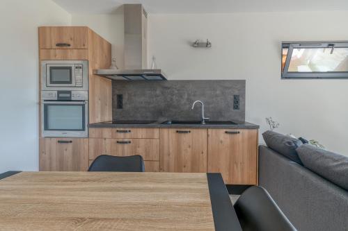 a kitchen with wooden cabinets and a table and a couch at La source Amélie in Saint-Pancrasse