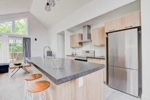 a kitchen with a stainless steel refrigerator and wooden cabinets at Chalet Beaulieu - Spa - Piscine - Sauna - Billard in Pont-Rouge