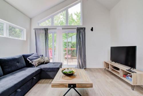 a living room with a blue couch and a tv at Chalet Beaulieu - Spa - Piscine - Sauna - Billard in Pont-Rouge