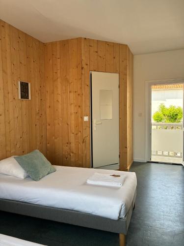 une chambre avec un lit avec des murs en bois et une fenêtre dans l'établissement LES BAIGNEURS, à Saint-Gilles-Croix-de-Vie