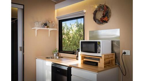 a kitchen with a counter with a microwave and a window at Manna Gum Retreat by Tiny Away in Allansford
