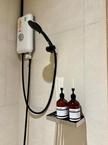 a shower head and two bottles on a shelf in a bathroom at Luana Hatyai house in Hat Yai