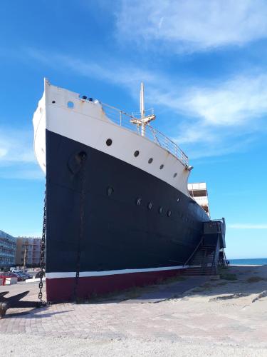 a large black and white boat sitting on the beach at Appart avec loggia en front de mer et superbe vue in Le Barcarès