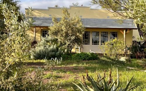 a yellow house with a garden in front of it at The Happy Place, private cottage with rustic pool in Van Wyksdorp