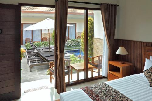 a bedroom with a bed and a balcony with a patio at Cening Ayu Sanur in Sanur