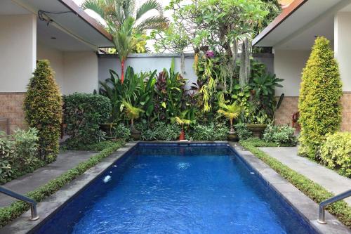 a swimming pool in a garden with trees and plants at Cening Ayu Sanur in Sanur