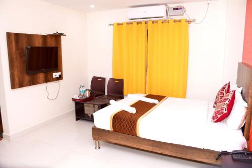 a hotel room with a bed and a television at Harsha Comforts in Chikmagalūr