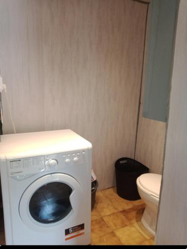 une machine à laver dans une salle de bain avec toilettes dans l'établissement Nid douillet à Cransac, à Cransac