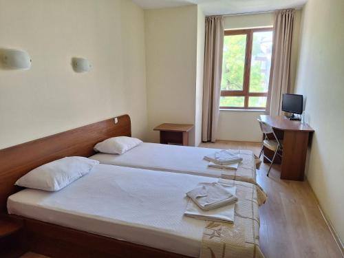 a bedroom with two beds and a desk and a television at Hotel Elica in Varna City