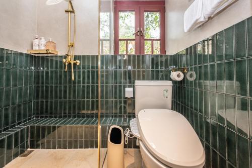 a green tiled bathroom with a toilet and a tub at TUIWA Garden Holiday Villa in Qingdao