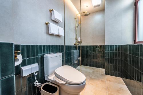 a bathroom with a toilet and green tiled walls at TUIWA Garden Holiday Villa in Qingdao