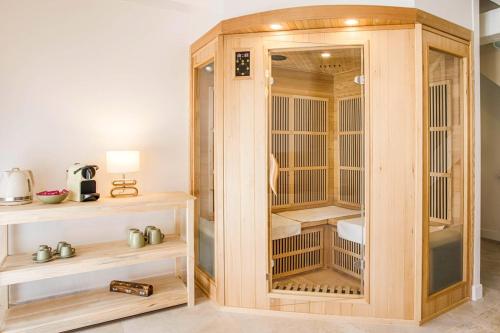 Maison Spa et Sauna, Cœur de la Normandie في Ranville: خزانة خشبية مع أبواب زجاجية في الغرفة