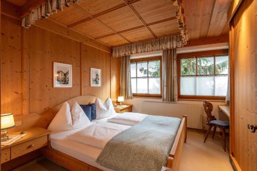 a bedroom with a bed and a desk and windows at Ferienwohnung Kober in Hopfgarten im Brixental