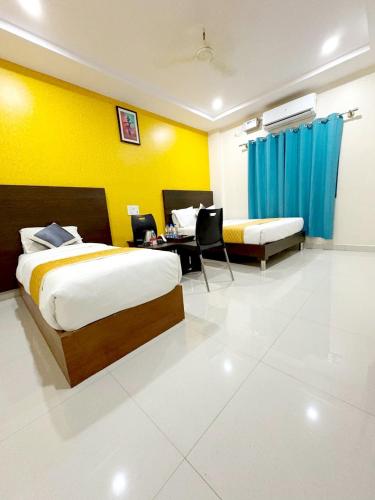 a hotel room with two beds and a desk in it at Harsha Comforts in Chikmagalūr
