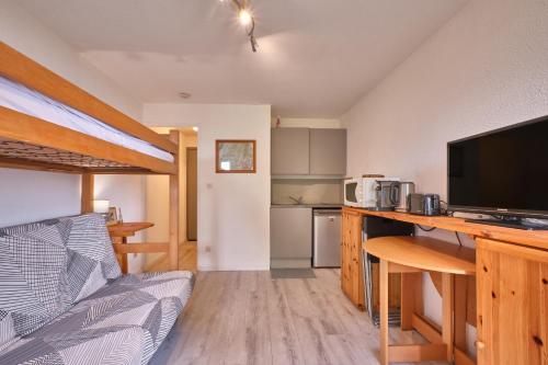 un salon avec un canapé et une télévision et une cuisine dans l'établissement Prapoutel pied des pistes, à Les Adrets