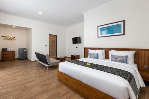 a hotel room with a large bed and a chair at Beach8 Canggu By Kerta Living in Canggu