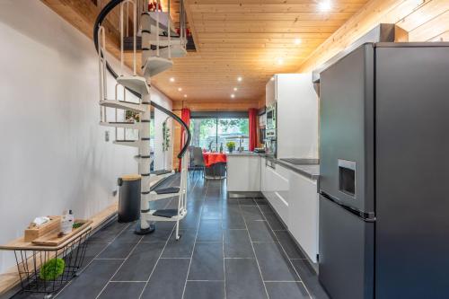  La cuisine est équipée de placards blancs et d'un réfrigérateur. dans l'établissement Le Chalet des Buch avec Spa, à Sanchey