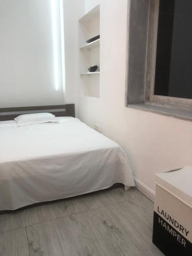 a white bedroom with a bed and a box at Mutamba Prime Stay in Luanda