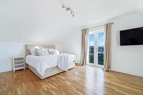 a white bedroom with a bed and a large window at 29 Fintra Bay with direct access to the beach in Saint Catherines