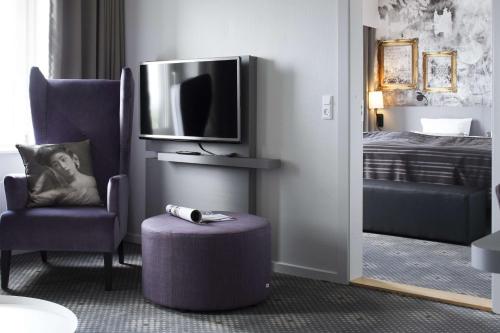 a room with a tv and a chair and a stool at Scandic Regina in Herning
