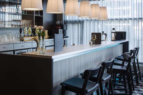 a bar with black chairs and a counter with lights at Scandic Regina in Herning