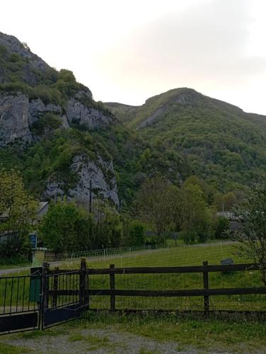 une clôture dans un champ avec des montagnes en arrière-plan dans l'établissement Duplex Apartment for 8 à 10 people with garden, à Campan