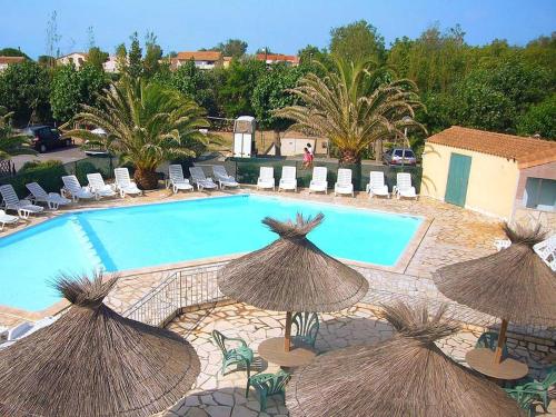 - une piscine avec des parasols et des chaises en paille dans l'établissement Maison à Marseillan plage, à Marseillan