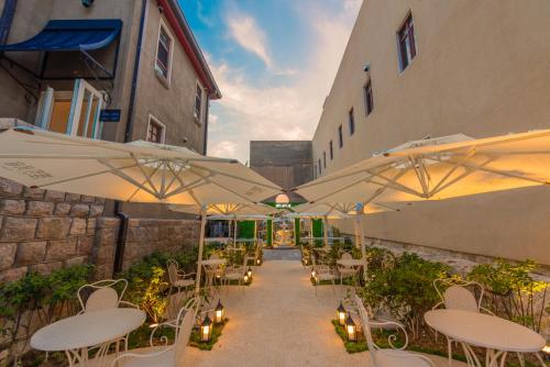 a patio with white tables and chairs and umbrellas at TUIWA Garden Holiday Villa in Qingdao
