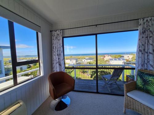 a room with a chair and a large window at Pura Vida by the Sea in Riverton