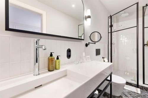 a white bathroom with a sink and a mirror at Hotel Astoria Vienna, Curio Collection by Hilton in Vienna