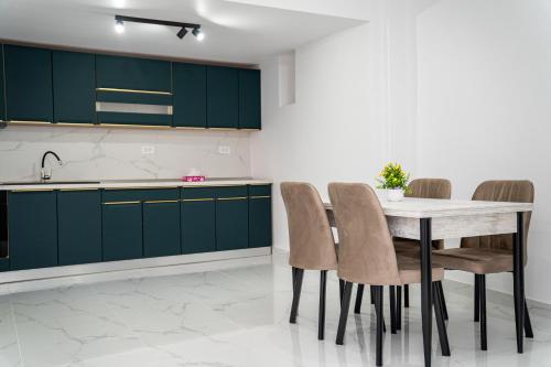 a kitchen with green cabinets and a table and chairs at Bogdan Premium Suites - Targu Jiu in Târgu Jiu