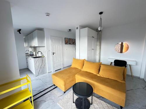a living room with a yellow couch and a kitchen at MOVEEN! Wynajem apartamentów we Wrocławiu! 10 minut od centrum in Wrocław